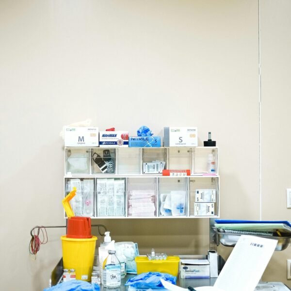 Neatly arranged medical supplies on a shelf in a hospital setting, featuring gloves, containers, and paperwork.
