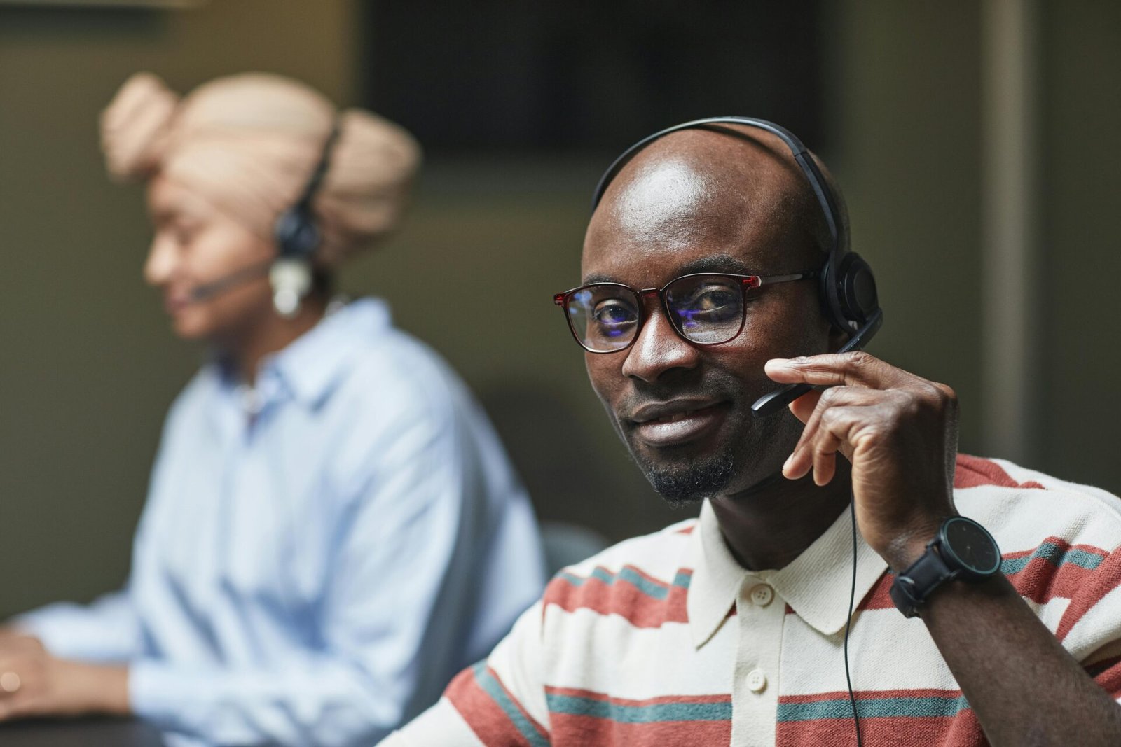 Friendly customer support representatives wearing headsets, working in an office setting.